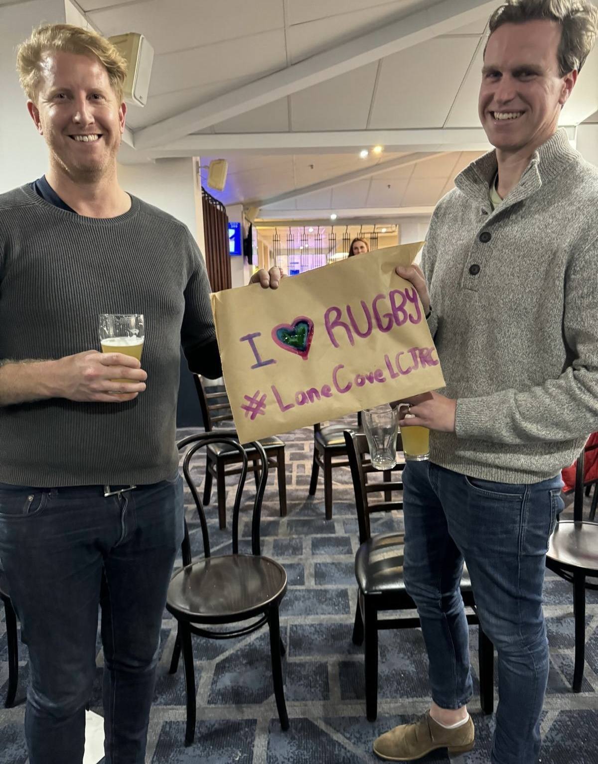 Lane Cove parents holding a handmade I love rugby sign at the Panthers Bathurst clubhouse