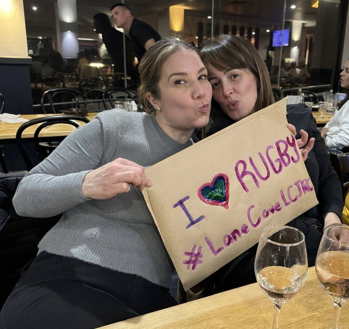 Lane Cove parents smiling with a handmade I love rugby sign at the Panthers Bathurst dinner