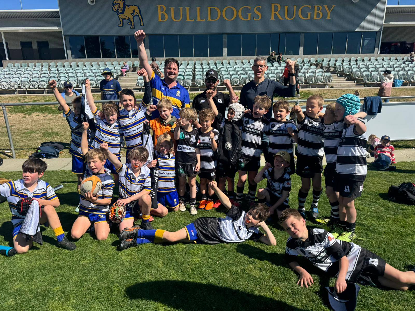 Lane Cove and country Minis players gathered together on the grass in front of the Bulldogs Rugby grandstand