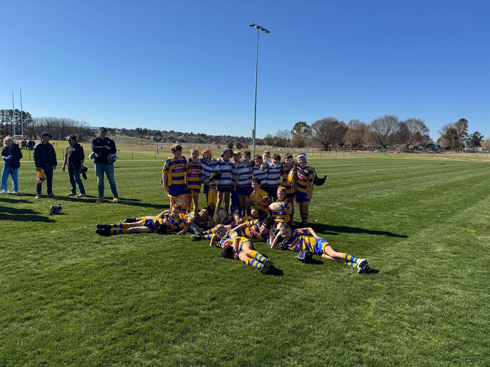 Lane Cove Minis players posing together on the Bathurst field under a clear blue sky