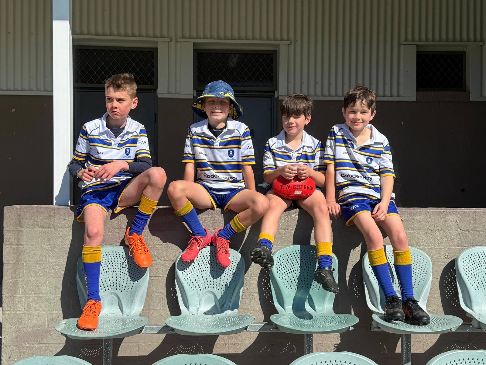 Lane Cove Minis players sitting in the Bathurst grandstand between games