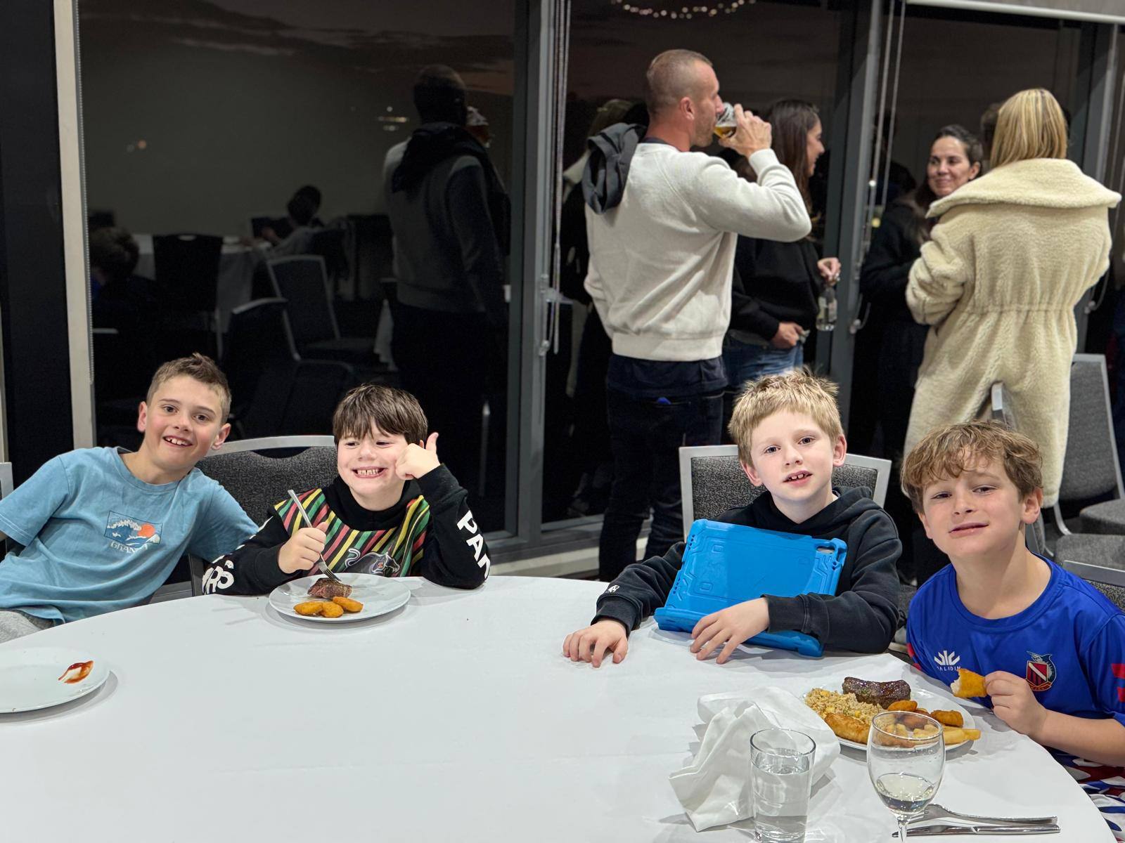 Lane Cove Minis kids smiling over dinner while parents chat in the background